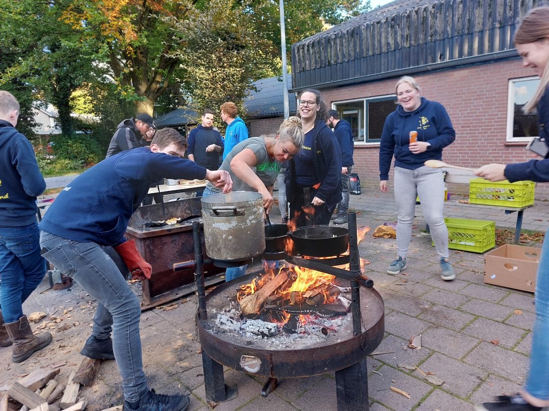 Samen koken boven het kampvuur tijdens de bivakcursus.