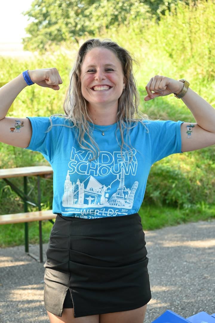 Vrijwilliger in een Kaderschouw shirt lacht en spant haar spierballen tijdens het trainingsweekend