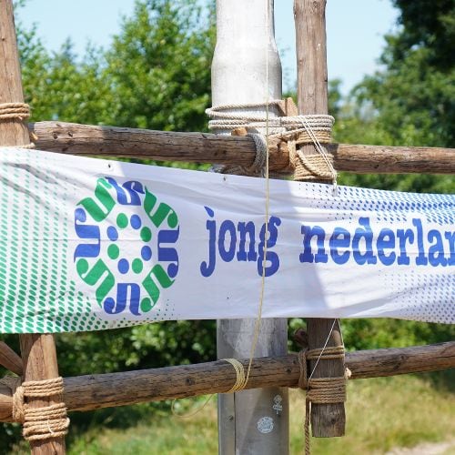Een spandoek van Jong Nederland aan een zelfgebouwde touwconstructie op het kampterrein