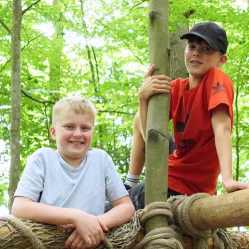Twee kinderen klimmen tijdens een buitenactiviteit van Jong Nederland