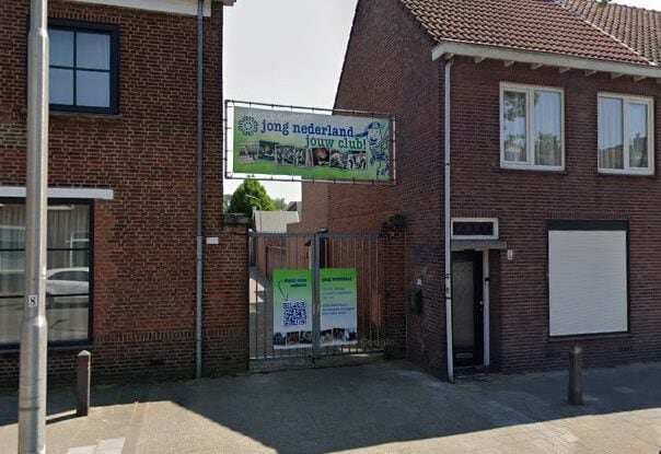 Gevel van een clubgebouw van Jong Nederland met een spandoek 'jong nederland - jouw club!' boven de poort