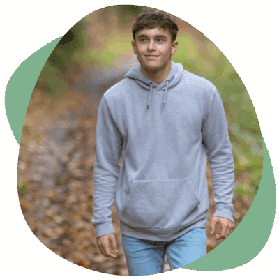 Tiener in een grijze hoodie wandelt door een herfstbos